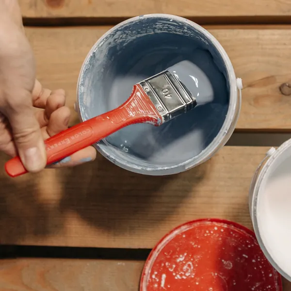 Brocha mojada en pintura azul sobre un bote de pintura